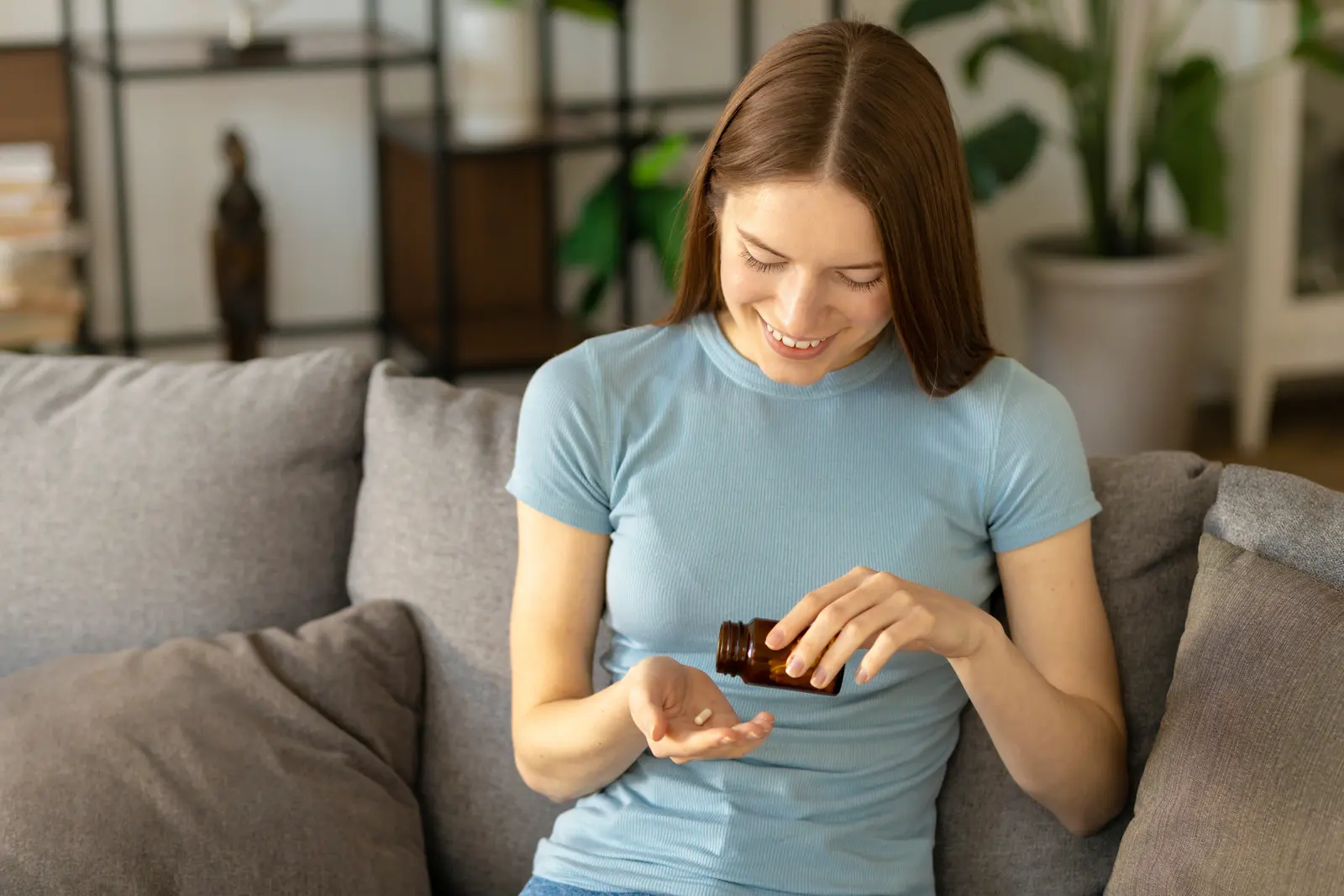Woman at home on her sofa, opening her medicine